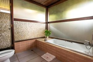 a bathroom with a tub and a toilet at The Buyan Resort Bedugul in Bedugul +27 photos