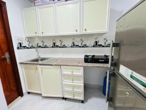 a kitchen with white cabinets and a sink and a refrigerator at 16 Villa in Sabkhah
