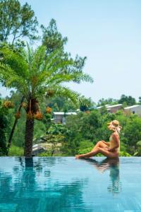 a woman sitting on the edge of a swimming pool at Villa Valley De Mango Hue in Thôn Châu Chữ