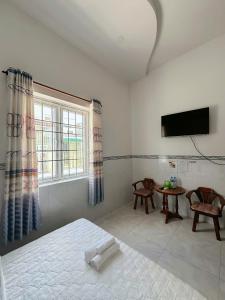 a bedroom with a bed and a tv and a table at Ngoc May Guesthouse in Chau Doc