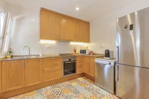 a kitchen with wooden cabinets and a stainless steel refrigerator at Villa Sol del Este, Es Castell in Es Castell