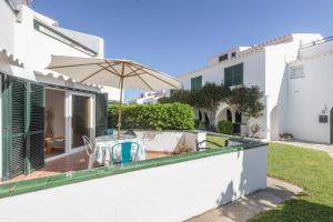 a patio with a table and an umbrella at Villa Sol del Este, Es Castell in Es Castell