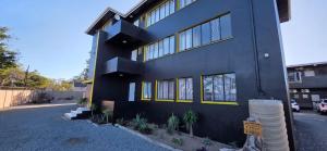 a black house with yellow windows on a street at Grace Villas 8 in East London
