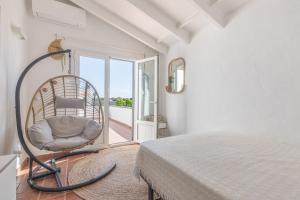 a bedroom with a bed and a chair and a balcony at Villa Sol del Este, Es Castell in Es Castell +25 photos