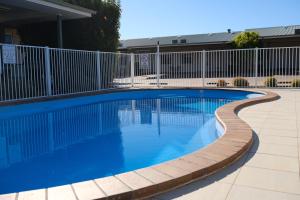 a swimming pool with a fence and blue water at Cobar Central Motor Inn in Cobar