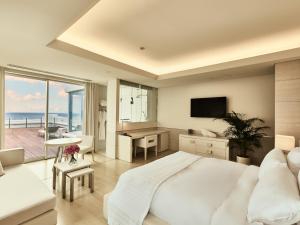 a white bedroom with a large bed and a view of the ocean at Hotel Greges in Munakata