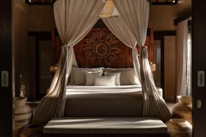 a bedroom with a canopy bed with white pillows at Dedary Resort & Spa Ubud by Ini Vie Hospitality in Ubud