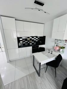 a white kitchen with a white table and chairs at Apartament Borys in Malbork