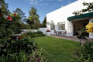 a backyard with a table and chairs and flowers at Greenhill Farm Cape Dutch Cottage Plettenberg Bay - 1 Bedroom Private Cottage in Plettenberg Bay