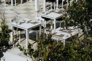 a group of white tables with plates on them at Polos Hotel Paros by GHH in Parikia