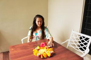 une femme assise à une table avec un bol de fruits dans l'établissement Santo Seaside Villas, à Luganville