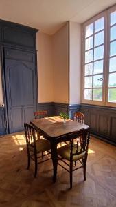 ein Esszimmer mit einem Holztisch und Stühlen in der Unterkunft Palais abbatial de Bourgueil in Bourgueil