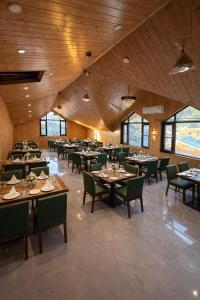 a large dining room with tables and green chairs at Hotel Belvior Estate in Srinagar