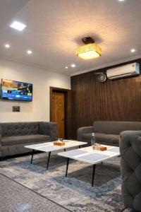 a living room with couches and a table and a tv at Hotel Belvior Estate in Srinagar