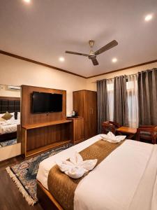 a hotel room with a bed and a flat screen tv at Hotel Belvior Estate in Srinagar +21 photos