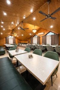 a dining room with tables and green chairs at Hotel Belvior Estate in Srinagar