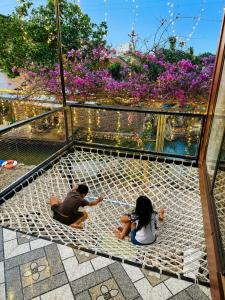two people sitting on a hammock in a garden at Tình's Homestay in Ninh Binh