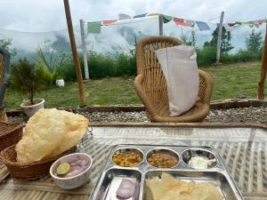 a table with a tray of food and a basket of food at Sari Highlands chopta Offbeat campsite in Ukhimath