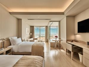 a hotel room with two beds and a desk at Hotel Greges in Munakata