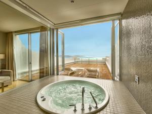 a bathroom with a tub with a view of the ocean at Hotel Greges in Munakata