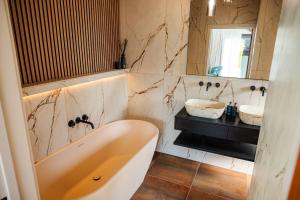 a bathroom with a tub and a sink and a mirror at Retreat 10 in Beccles +7 photos