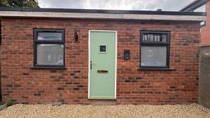 a brick building with a green door and two windows at Studio Flat in Seymour Road in Bristol