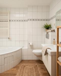 a bathroom with a tub and a toilet and a sink at Stilvolles Apartment mit Wintergarten, Balkon & Parkblick - VILLA KAETHE am Kurpark in Warnemünde