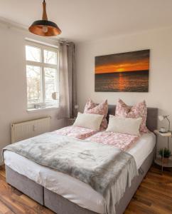 a bedroom with a large bed with pink pillows at Stilvolles Apartment mit Wintergarten, Balkon & Parkblick - VILLA KAETHE am Kurpark in Warnemünde