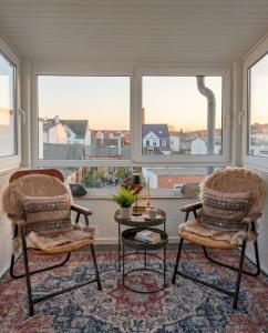 two chairs and a table in front of a window at Stilvolles Apartment mit Wintergarten, Balkon & Parkblick - VILLA KAETHE am Kurpark in Warnemünde