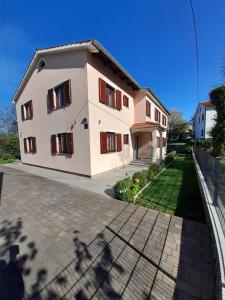a white house with red shuttered windows and a driveway at Villa Marija in Opatija