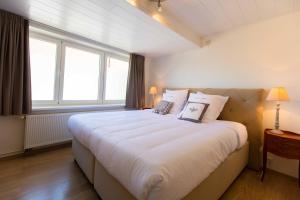 a bedroom with a large white bed with windows at Queen Astrid in Ieper