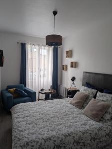 a bedroom with a large bed and a blue chair at Les chambres du vieux quartier in Thouars