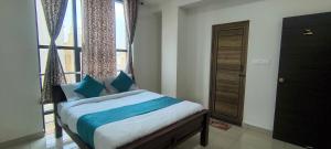 a bedroom with a bed with blue pillows and a window at Sky Light Mysore in Mysore South