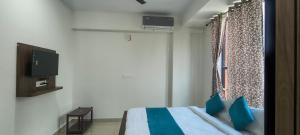 a bedroom with a bed with blue pillows and a window at Sky Light Mysore in Mysore South
