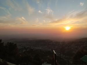 a sunset over a city with the sun in the sky at peak&valley homestay in Dharmsāla