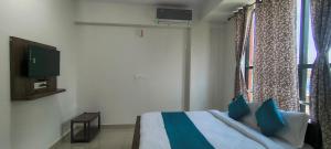 a bedroom with a bed with blue pillows and a window at Sky Light Mysore in Mysore South