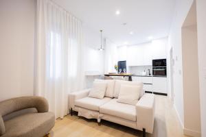 a white living room with a white couch and a kitchen at Apartamentos La Búsqueda in Cuenca