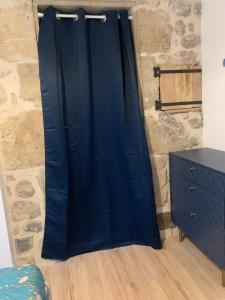 a blue curtain in a room with a stone wall at Le Mas des Sources - Appartement in Vals-les-Bains +3 photos
