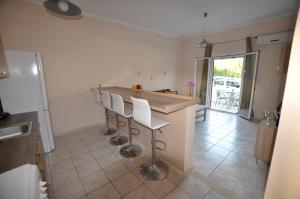 a kitchen with a bar with white stools at Ammos in Roda