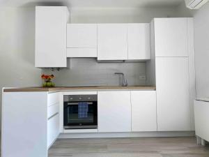 a white kitchen with white cabinets and a sink at Studio Artemisia in Grado