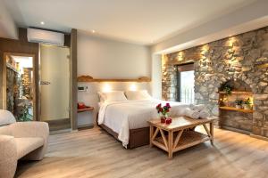 a bedroom with a large bed and a stone wall at Evoras Boutique Hotel in Xirokámbion