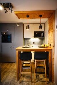 une cuisine avec un comptoir et deux chaises sur un îlot de cuisine dans l'établissement La Chabane, à Chamonix-Mont-Blanc