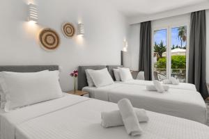 a bedroom with three beds with white sheets and a window at Polos Hotel Paros by GHH in Parikia