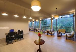 a large lobby with chairs and tables and windows at Abad Brookside Wayanad in Vythiri