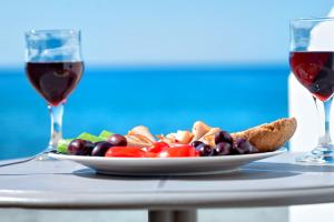 a plate of food on a table with two glasses of wine at Fodele Beachfront Apts in Fodele