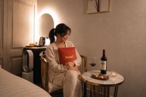 a woman sitting in a chair with a book and a bottle of wine at Instar Hotel in Suwon