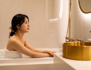 a woman sitting in a bath tub at Instar Hotel in Suwon