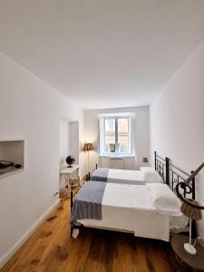 a white bedroom with a large bed and a window at Dimora storica - Palazzo Barabesi in Siena