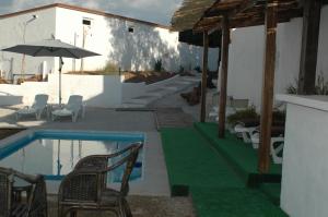 a patio with a pool and chairs and an umbrella at Jingtu Wellness & Spa Resort in Comares