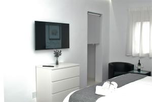 a bedroom with a bed and a dresser with a tv on the wall at Jingtu Wellness & Spa Resort in Comares